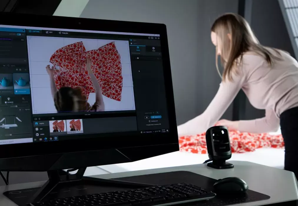 Fotograf poprawiający ubranie z kwiatowego materiału z podglądem na monitorze