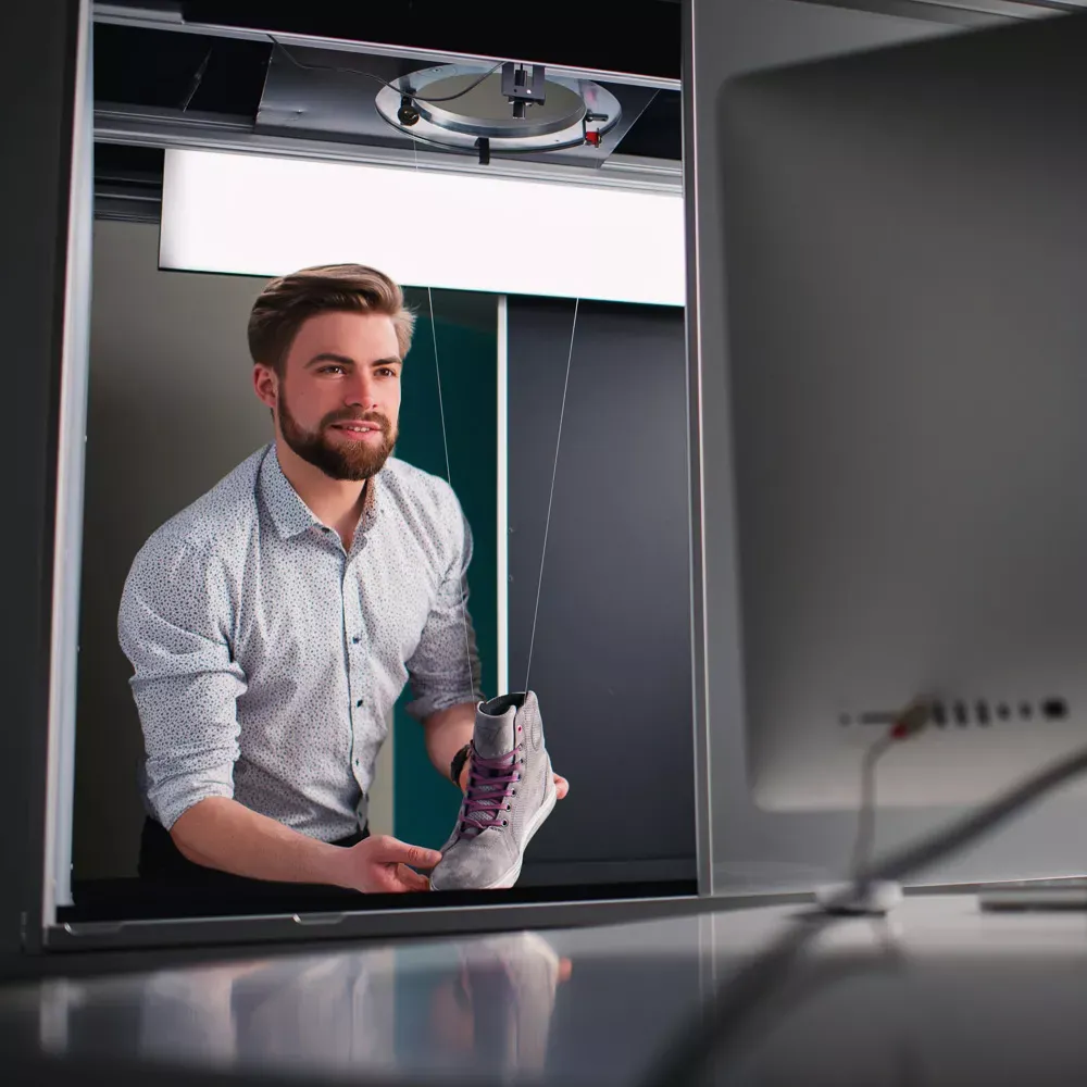 Mężczyzna przygotowujący produkt do profesjonalnej fotografii obuwia