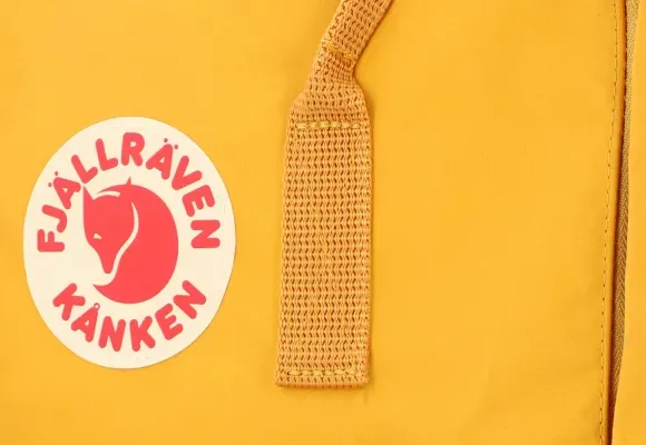 Zbliżenie na logo i pasek żółtego plecaka Kanken