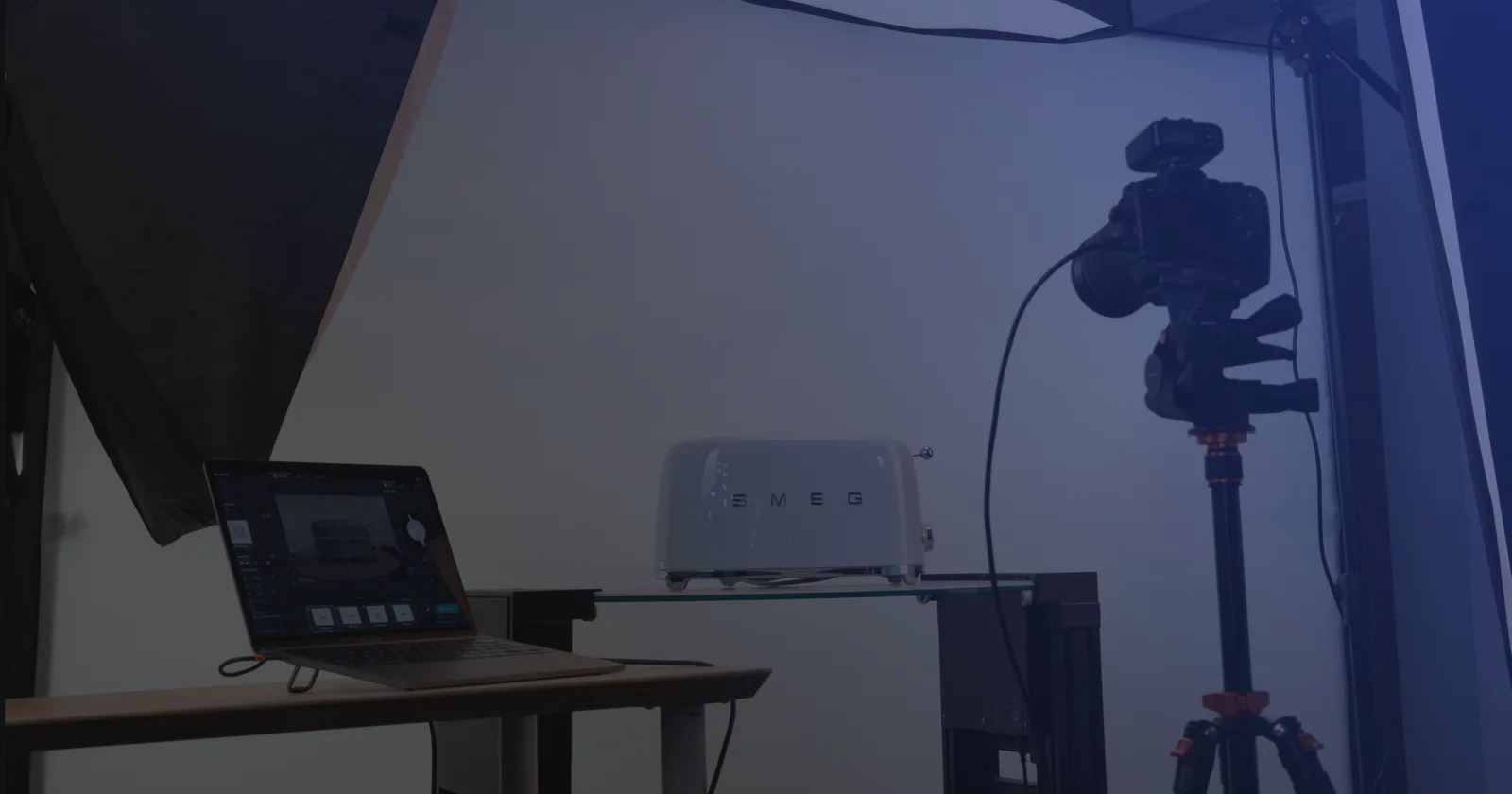 Stanowisko do fotografii produktowej z tetheringiem - laptop z oprogramowaniem obok aparatu na statywie i produktu na szklanej półce