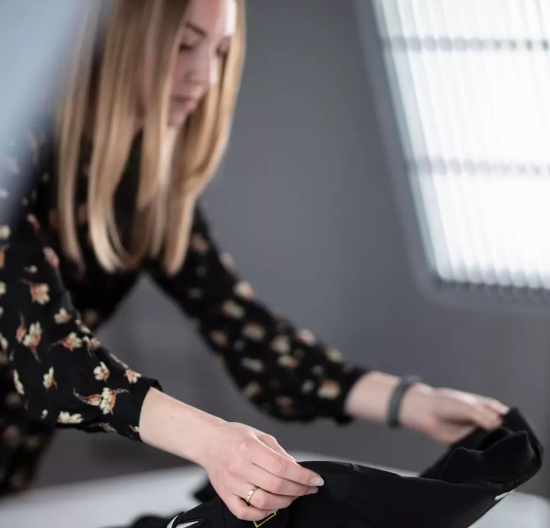 Stylista produktowy układający czarne ubranie do sesji flat lay